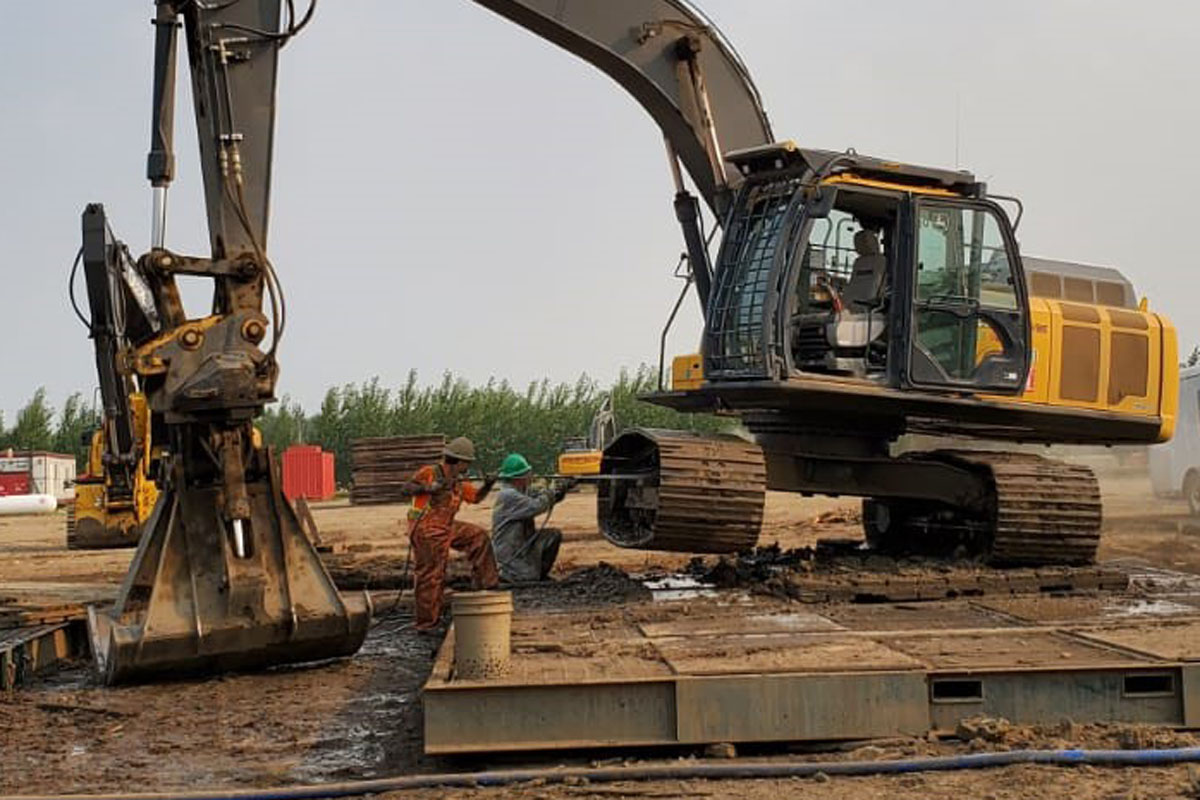 Empire Oilfield labourers doing maintenance on excavator